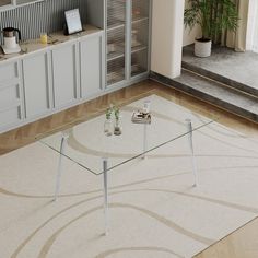 a glass coffee table sitting on top of a wooden floor next to a white rug