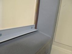 the corner of a room with a metal shelf on it's side and a white wall in the background