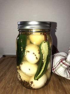 a jar filled with pickles and cucumbers on top of a wooden table