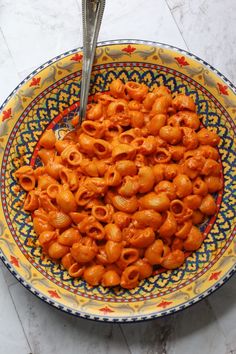 a bowl filled with macaroni and cheese sitting on top of a marble table