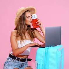 a woman sitting on a suitcase and using her laptop