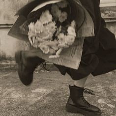 a person in black boots is holding flowers