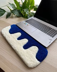 an open laptop computer sitting on top of a wooden desk next to a blue and white rug