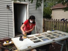 a woman in a red shirt is sanding glass on a table with a power drill