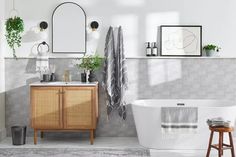 a white bath tub sitting next to a wooden cabinet in a bathroom under two mirrors