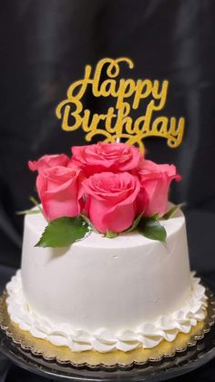 a white cake topped with pink roses and the words happy birthday written on top of it