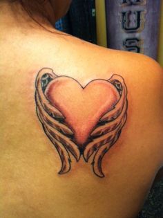 the back of a woman's shoulder with an angel heart tattoo design on it