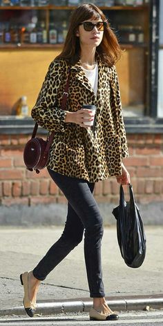 a woman is walking down the street with her handbag and coffee in her other hand