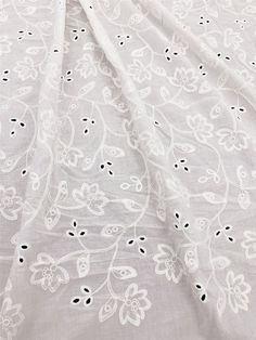 an embroidered white fabric with black dots and floral designs on it, as seen from the side