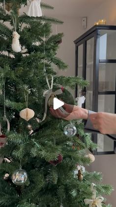 someone is decorating a christmas tree with ornaments