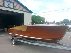 a wooden boat is parked in front of a garage