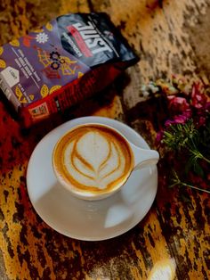 a cappuccino on a white saucer next to a bag of coffee