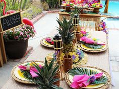 the table is set with pineapples and other tropical decorations for an outdoor party