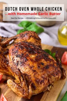 a close up of a chicken on a cutting board with tomatoes and herbs in the background