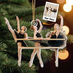 three ballerinas hanging from a christmas tree with an ornament in the shape of a photo