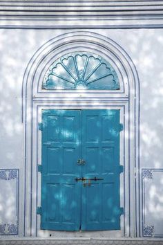 a blue door is in front of a white building with arches and arched doorways