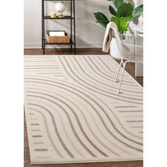 a white rug with wavy lines on the floor in front of a book shelf and potted plant