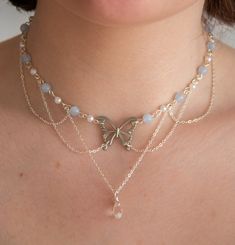 This necklace features delicate pastel blue beads, lustrous pearls, and draped chains, creating a layered, fairy and ethereal look. In the heart of this necklace, a captivating butterfly pendant and a sparkling clear crystal pendant add a touch of timeless beauty.  The layers of draped chains add depth and dimension to the necklace, allowing it to rest gracefully against your neckline, accentuating your natural beauty. The delicate nature of this piece ensures it is suitable for any occasion, from casual outings to formal events, making it a versatile addition to your jewellery collection. Elevate your style with this exquisite accessory, effortlessly blending sophistication with a touch of enchantment.  The pastel blue beads interspersed between the pearls create a harmonious colour palet Fairy Pearl Necklace, Ideas For Necklaces With Beads, Ethereal Jewelry Necklaces, Crystal Necklaces Ideas, Crystal Handmade Jewelry, Fancy Beaded Necklaces, Chain Necklace With Beads, Necles Design, Bead Wire Necklace