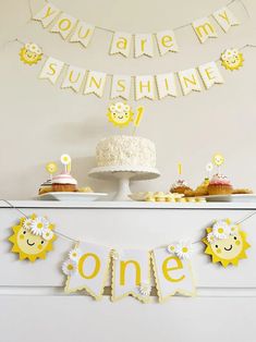 a cake and cupcakes on a table with bunting banner in the background