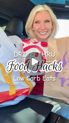 a woman sitting in the back seat of a car holding up some food and bags