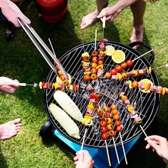 several people are grilling skewers full of food