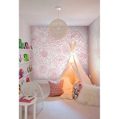 a teepee tent in a child's bedroom with pink flowers on the wall