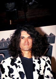 a man with long hair wearing a white and black jacket