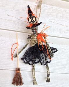 a skeleton dressed up as a witch holding a broom