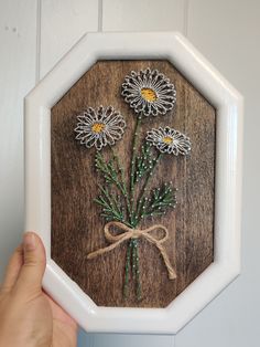 a hand holding a frame with flowers on it