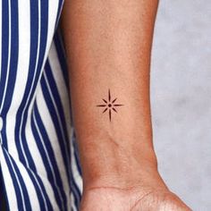 a woman's wrist with a small star tattoo on the left side of her arm