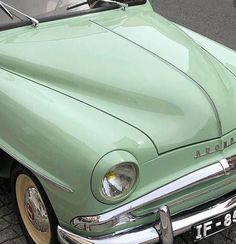 an old green car is parked on the street