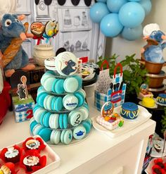 a table topped with lots of desserts and balloons in the shape of animals sitting on top of each other