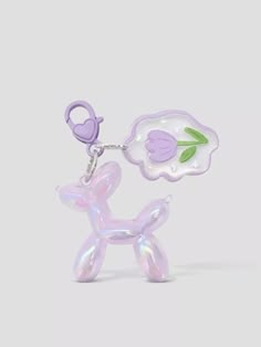 a keychain with a small purple dog on it's side and a flower in the middle