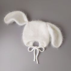 a white knitted bunny hat with ears and tail on a gray background, close up