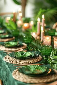 the table is set with green plates and place settings, candles and greenery in the background