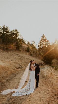 a bride and groom kissing on the side of a dirt road