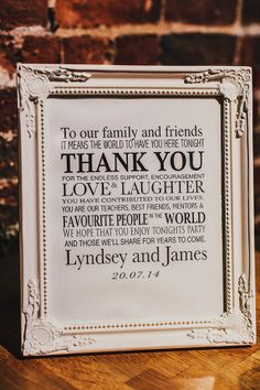 a white frame with the words thank you in different languages on it sitting on a wooden table