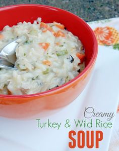 a bowl of creamy turkey and wild rice soup on a white place mat with a spoon in it