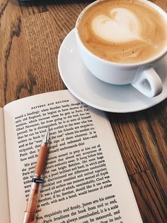 a cup of coffee sitting on top of an open book