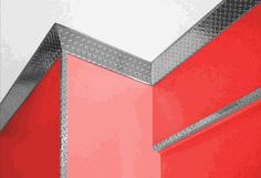 the corner of a building with red walls and metal trimmings on it's sides