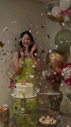 a woman standing in front of a cake surrounded by balloons and confetti