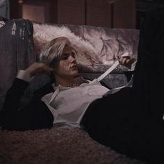 a woman laying on top of a couch next to a piece of luggage and holding a pair of scissors