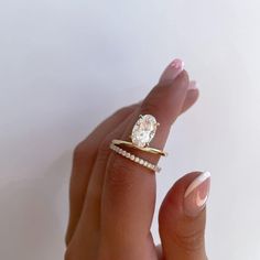 a woman's hand holding an engagement ring with a diamond on the top and side