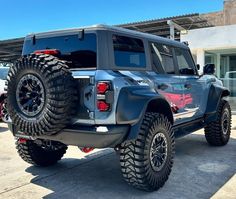 a jeep parked in front of a building with large tires on it's sides