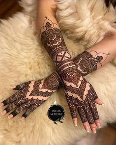 a woman's hands with henna tattoos on her arm and hand, sitting next to a furry animal