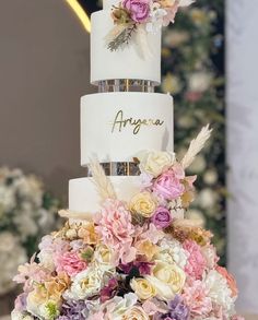 a three tiered wedding cake with flowers on top