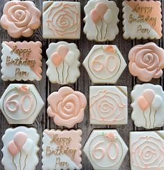 decorated cookies with pink and white frosting are arranged on a wooden surface, including roses