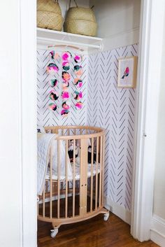 a baby's crib in the corner of a room with pink and white wallpaper