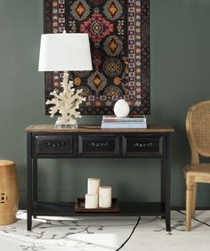 a table with two drawers and a lamp on it in front of a wall hanging