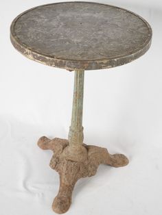 an old metal table with two legs and a small round top on a white background